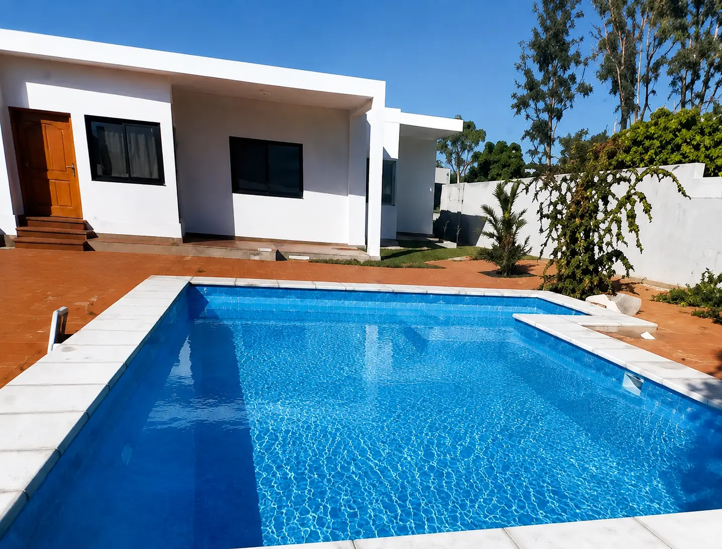 Referência visual de piscina rectangular compacta junto a uma residência