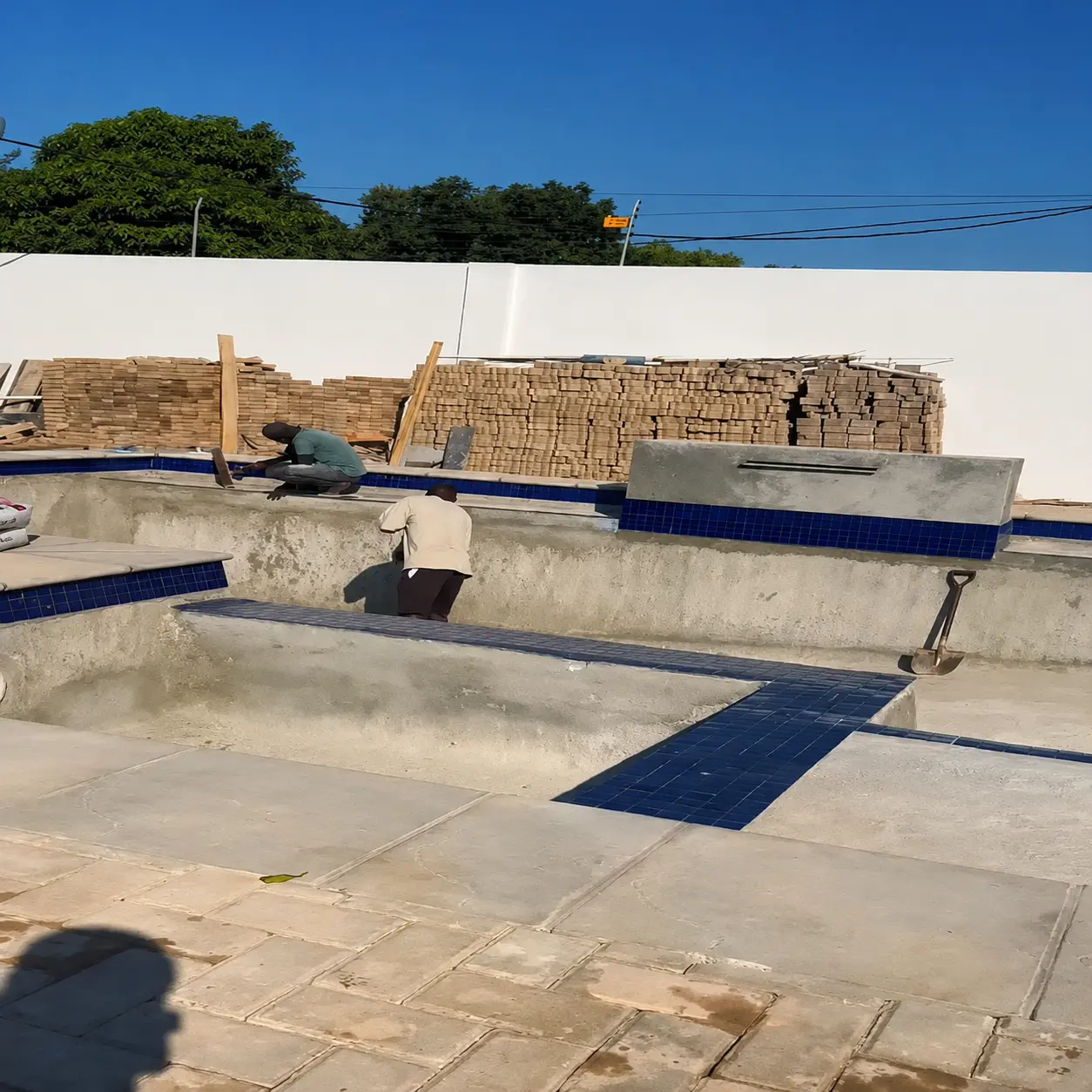 Trabalhadores da Zefas a executar acabamentos numa piscina em construção